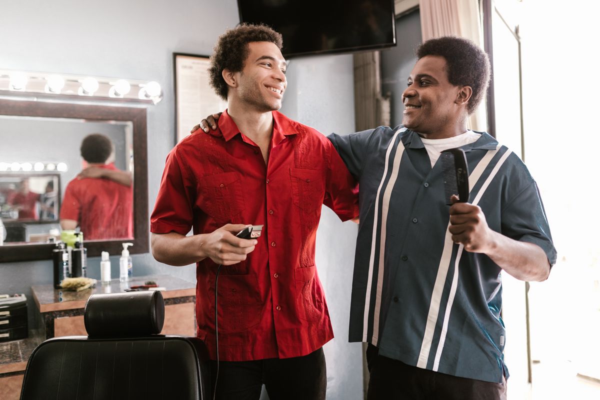 Two barbers laughing together in their barbershop